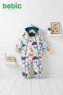 Baby wearing Bebic Dino Adventure padded snowsuit, cozy winter clothing with dinosaur print and warm, quilted design.